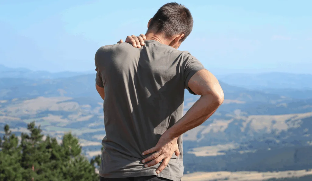 a hiker holding his back and neck on the hiking trail